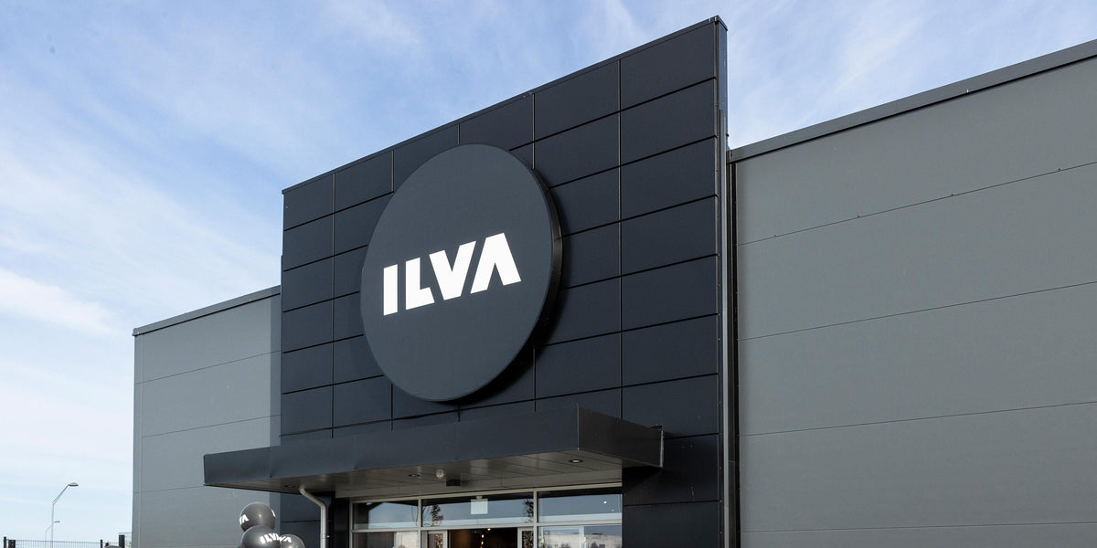 ILVA-butikens fasad med stor rund logotyp ovanför entrén, ballonger och skyltning för grand opening.