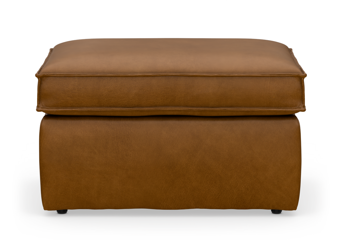 Brun läderpall/ottoman med mjuk kuddtopp, frilagd mot vit bakgrund.