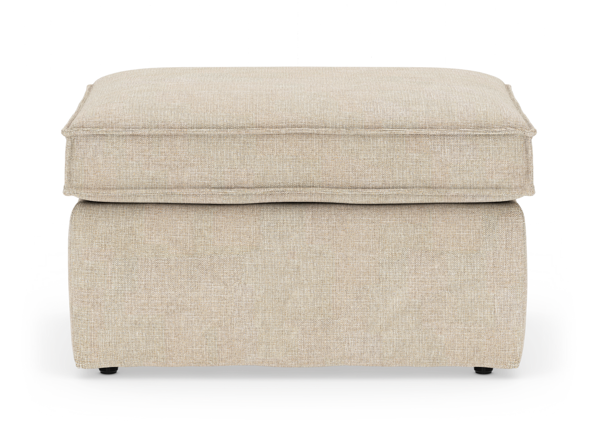 Beige fotpall i tyg med mjuk kuddtopp, frilagd mot vit bakgrund.