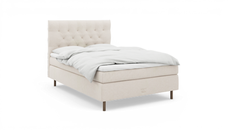 Beige stoppad säng med knapptuftad sänggavel och vit bäddning, frilagd mot vit bakgrund.