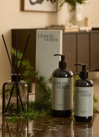 LEMON VERDE hand soap och handkräm på bord med doftpinnar och gröna kvistar i hemmiljö.