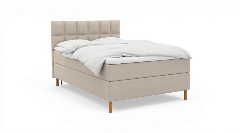 Beige, stoppad säng med kvadratiskt tuftad sänggavel, vita sängkläder och träben på vit bakgrund._ps