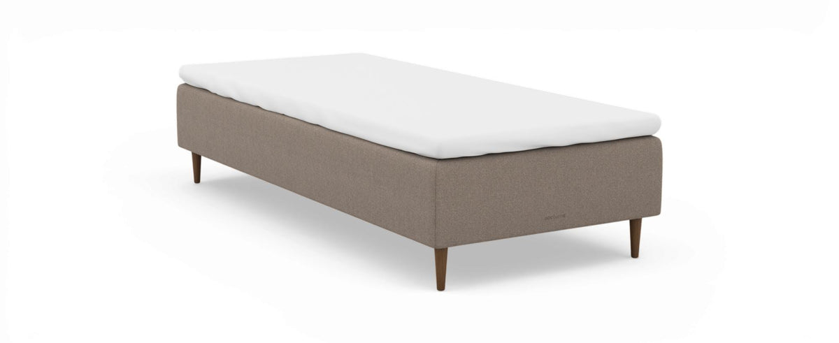 Beige stoppad enkelsäng med vit bäddmadrass och träben, nocturne på sidan, frilagd på vit bakgrund.