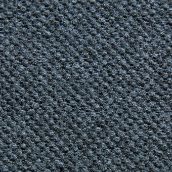 Närbild av mörkblå texturerad vävd textil med prickigt, diagonalt mönster.