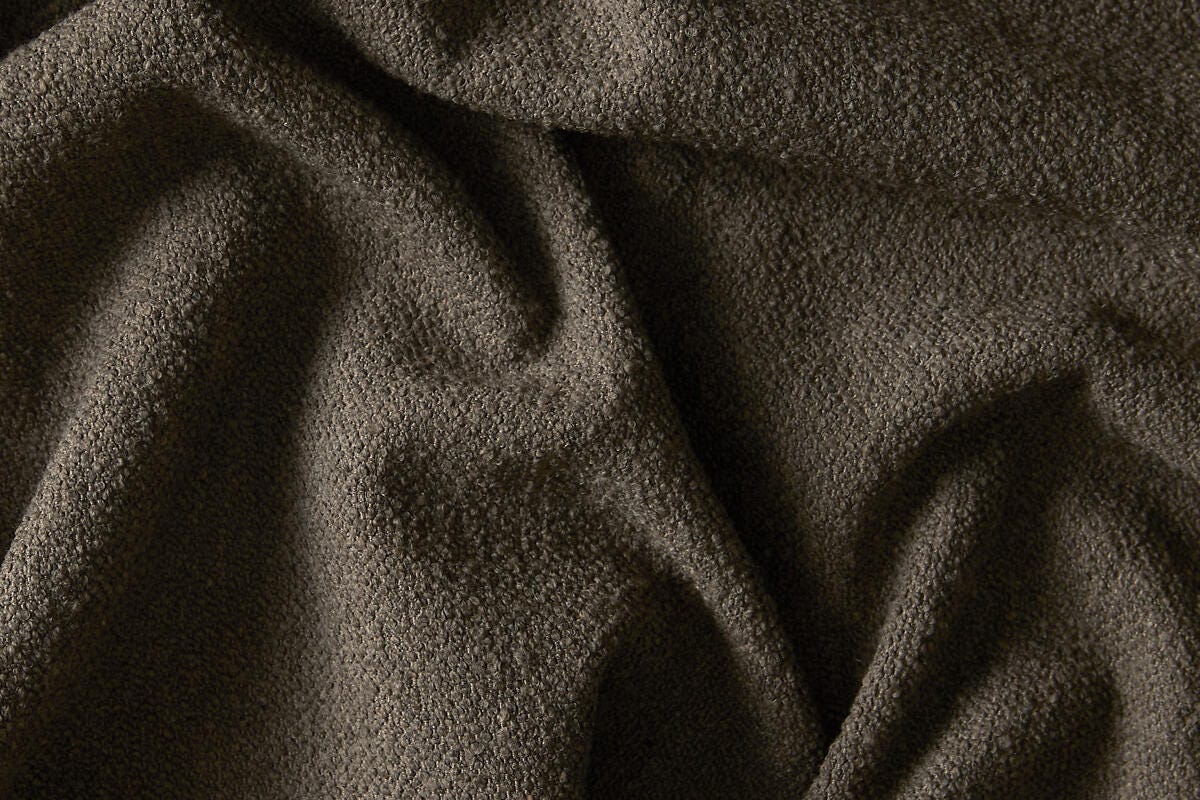 Närbild av draperat brunt bouclétyg med mjuk textur.