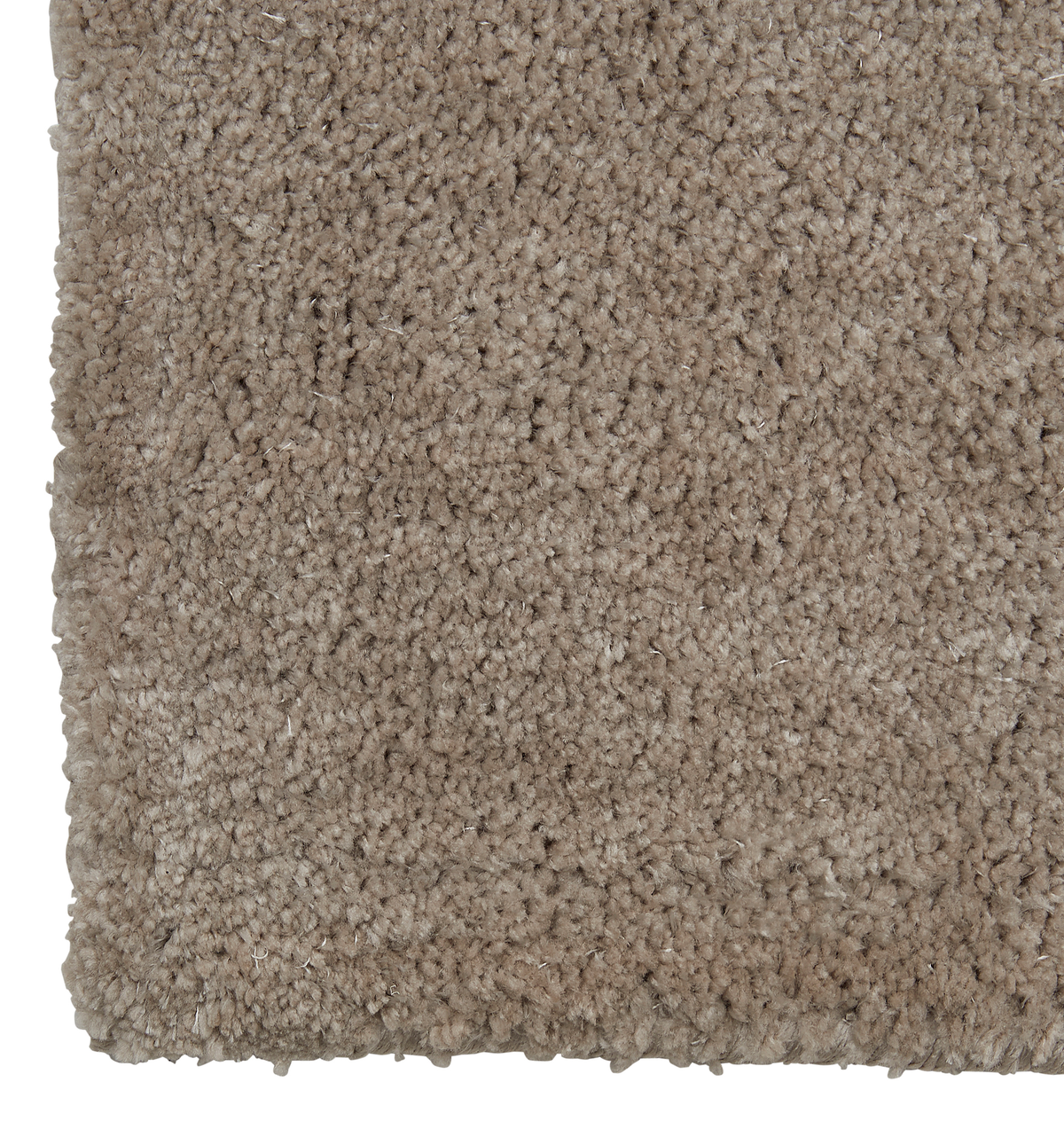 Närbild av beige, mjuk ryamatta med tjock lugg i hörnet.