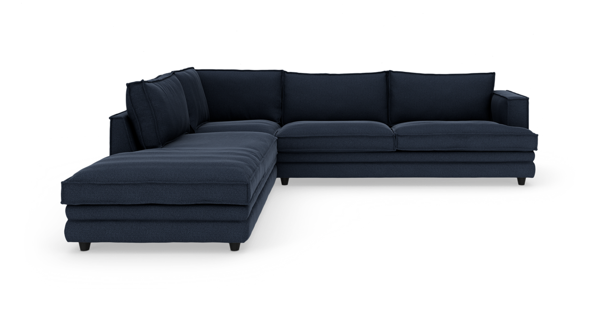 Mörkblå L-soffa med divan till vänster, frilagd mot vit bakgrund.