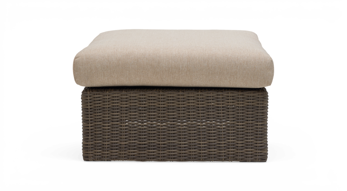 Framifrån av en kvadratisk ottoman med beige dyna och brun flätad rottingbas på vit bakgrund.