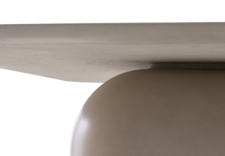 Närbild av en minimalistisk borddetalj: ljus, plan bordsskiva möter en rundad beige pelarbas i studiobelysning.
