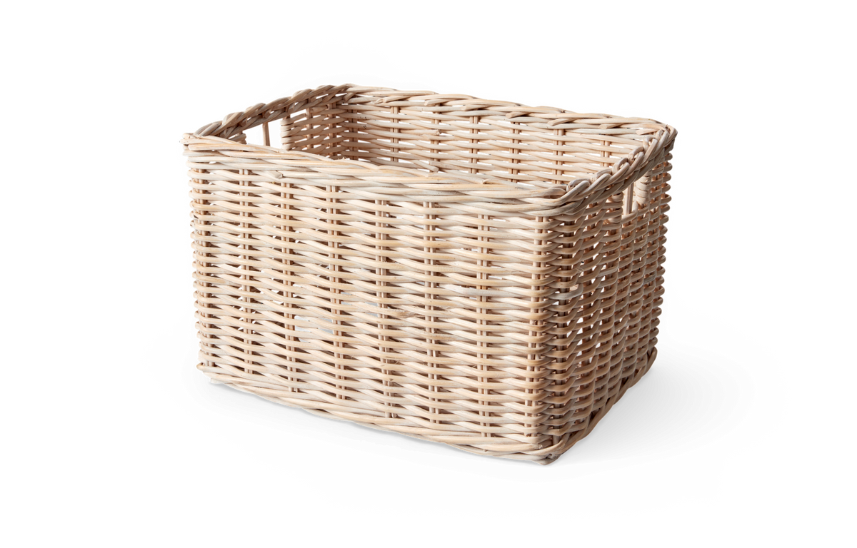 Ljusbeige rektangulär flätad rottingkorg med integrerade handtag, frilagd på vit bakgrund.