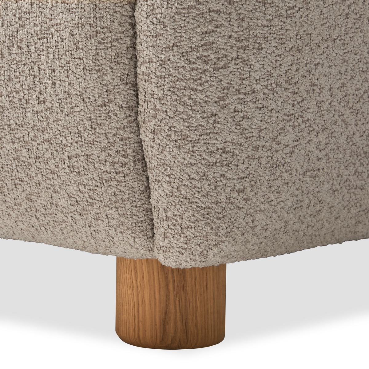 Närbild på soffhörn i beige bouclé med runt ben i ek.