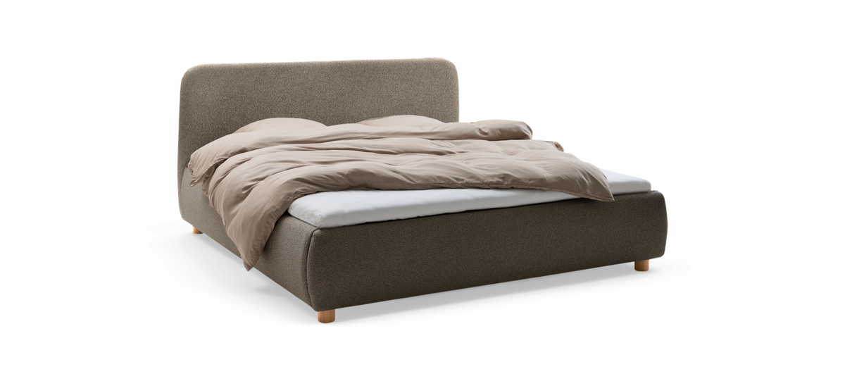 Uppbäddad dubbelsäng i beige med mjuk dyne och polstrad sänggavel, frilagd mot svart bakgrund.