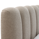 Närbild av rundad, kanalquiltad sänggavel i beige bouclé.