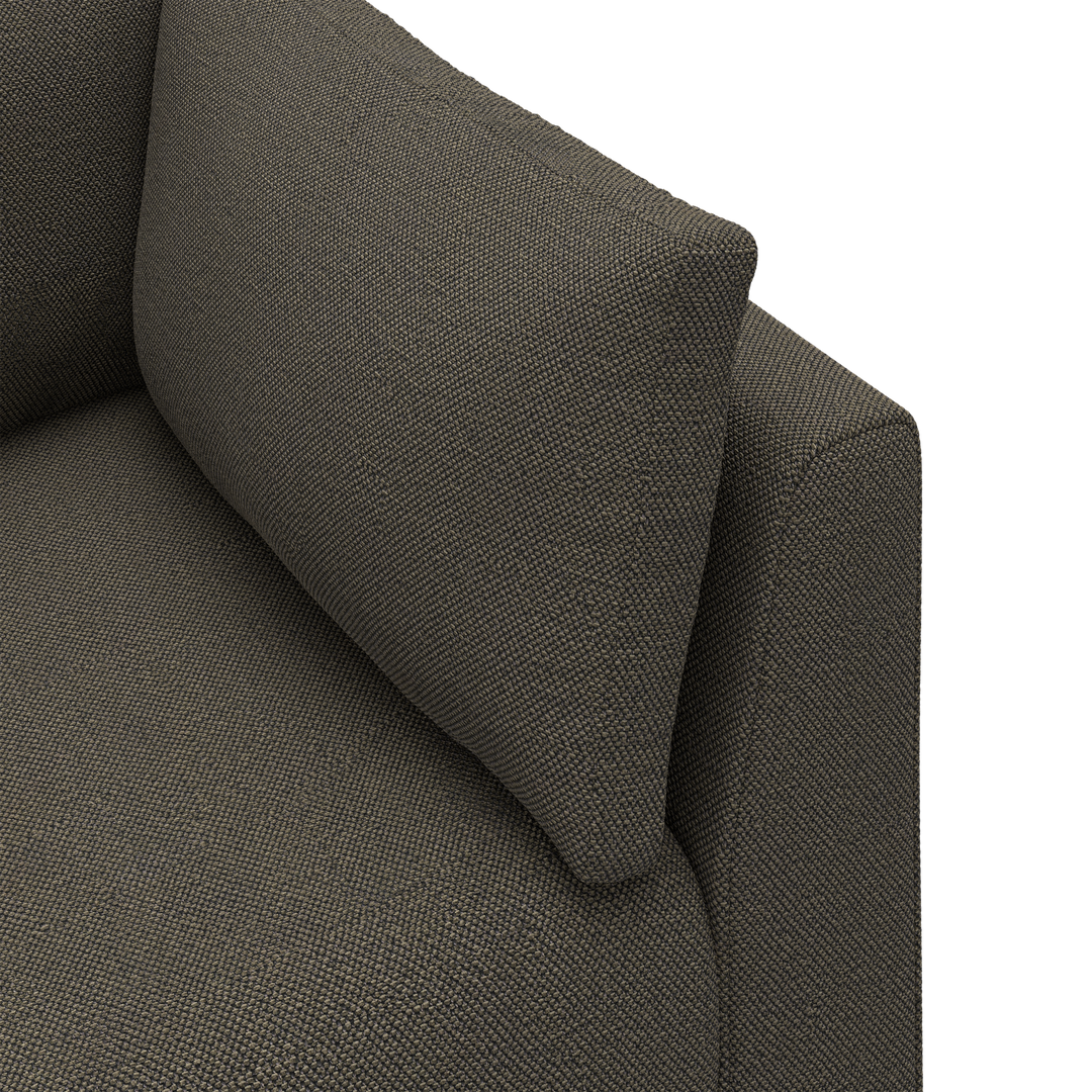 Närbild av ett mörkgrått soffhörn i grovt, texturerat tyg med en lös ryggkudde.