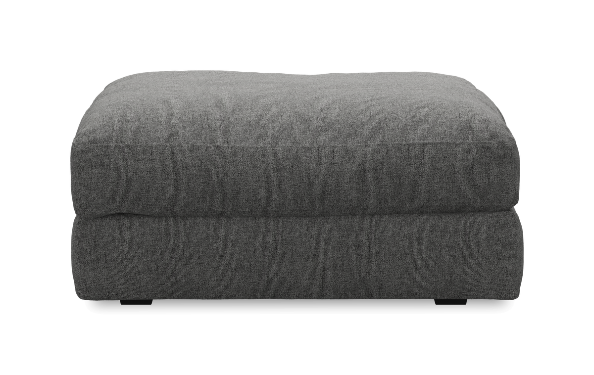Grå rektangulär, tygklädd ottoman/fotpall sedd rakt framifrån.
