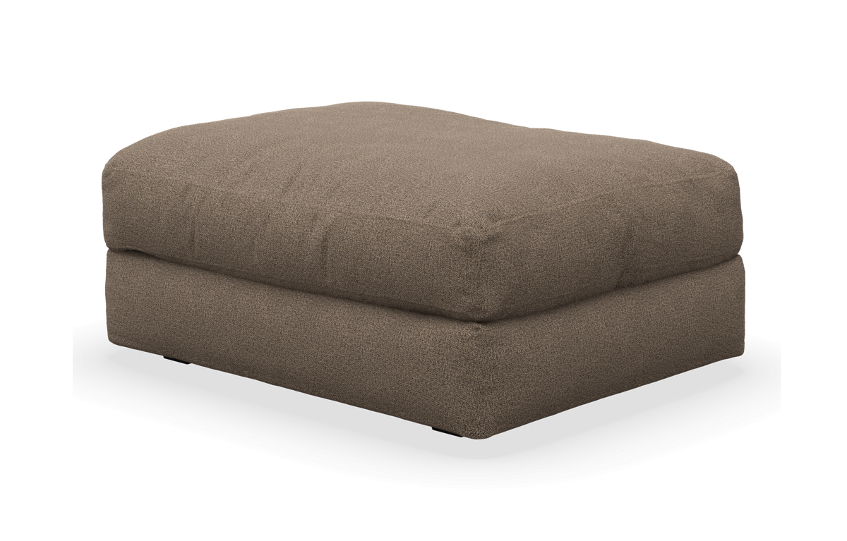 Brun, textilklädd ottoman/fotpall i mjuk, kubformad design, frilagd på vit bakgrund.