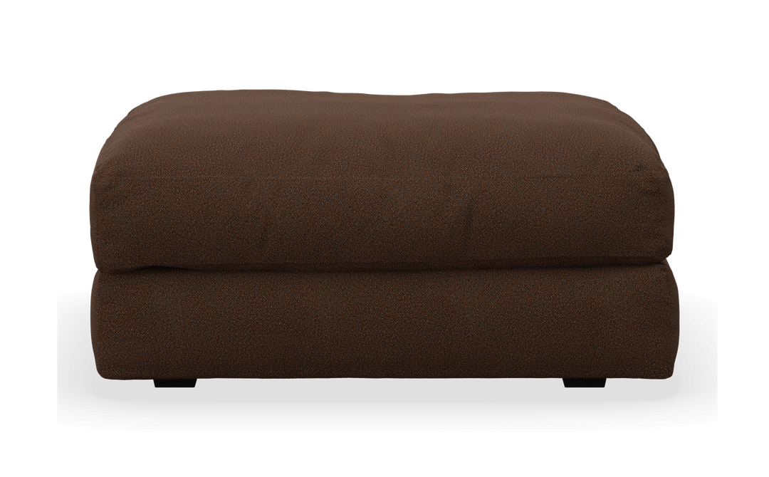 Brun, stoppad ottoman/puff i tyg, frilagd mot vit bakgrund, frontvy.