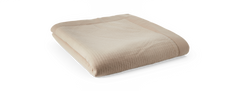 Vikad beige quiltad pläd/överkast med bred kant mot svart bakgrund.