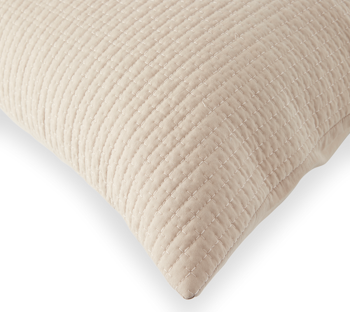 Beige quiltad kudde med korsstygnsmönster på svart bakgrund.