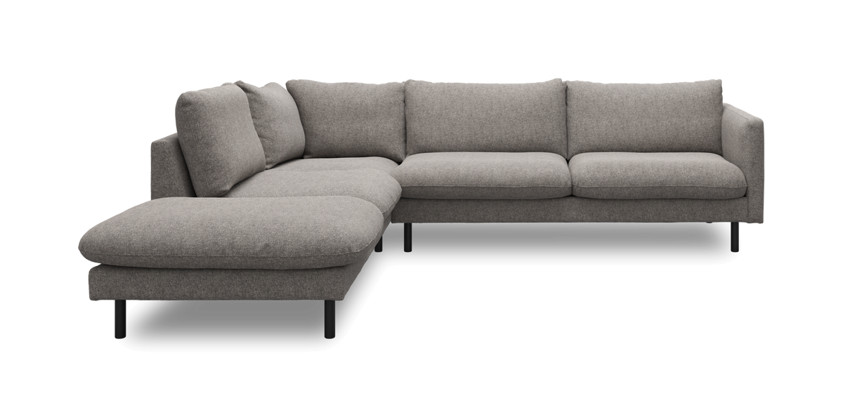 Grå L‑soffa med schäslong och slanka svarta ben i modern design.