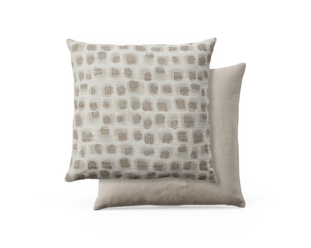 Två beige prydnadskuddar; den främre med upphöjt rutprickigt mönster i taupe på creme, den bakre i slät linnebeige.