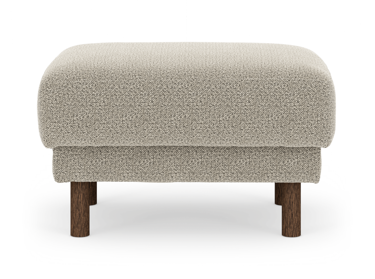 Beige fotpall i tyg med runda ben i mörkt trä, frilagd mot vit bakgrund.