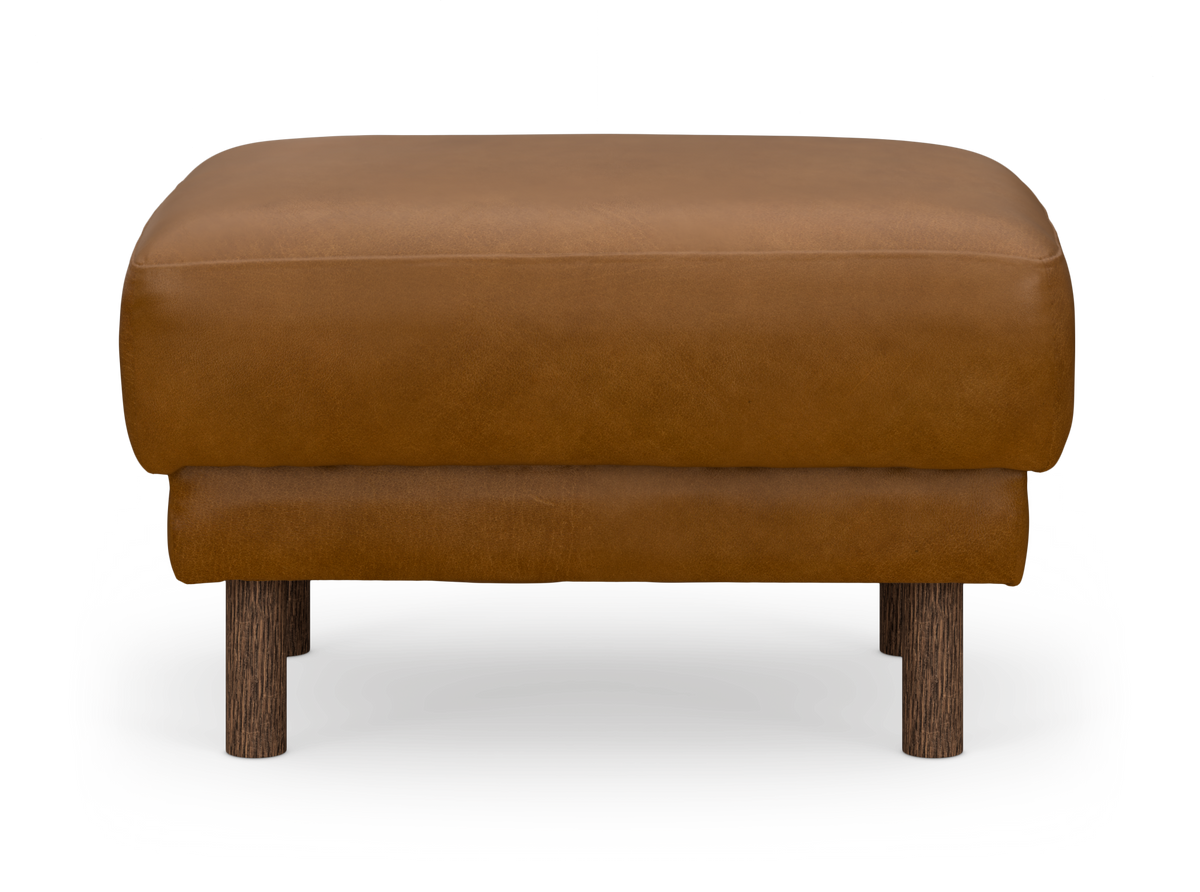 Brun läder-ottoman/pall med runda mörka träben, frontvy mot vit bakgrund.