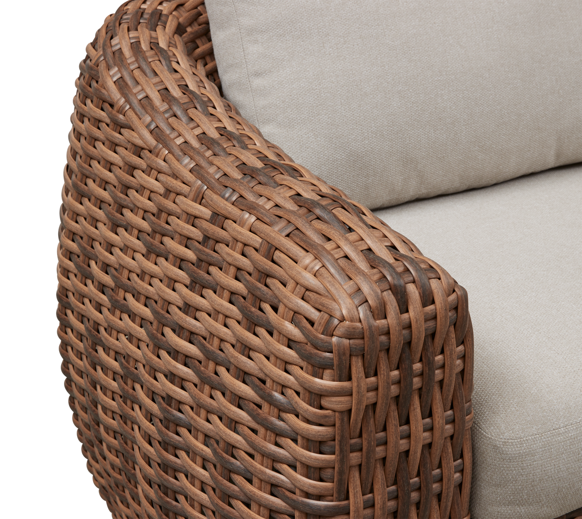 Närbild av flettat brunt rottingarmstöd på soffa med beige dynor.
