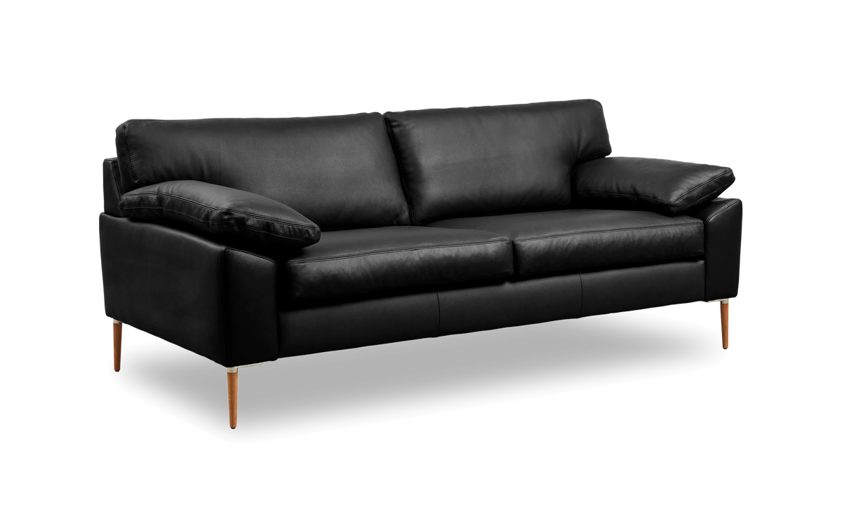 Svart lädersoffa med träben, tresits, fotograferad snett framifrån mot svart studiobakgrund.