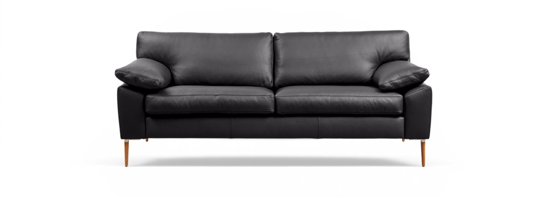 Svart lädersoffa med två sittkuddar, lösa ryggkuddar och träben, frilagd mot svart bakgrund.