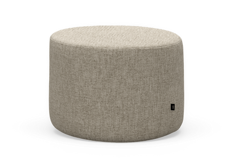 Rund beige tygpuff/ottoman frilagd mot vit bakgrund.