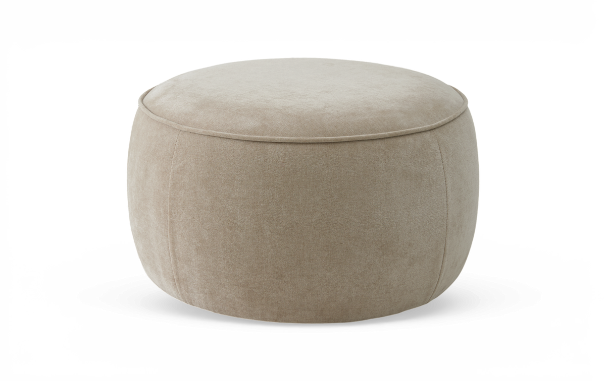 Beige rund puf/ottoman i tyg mot vit bakgrund.