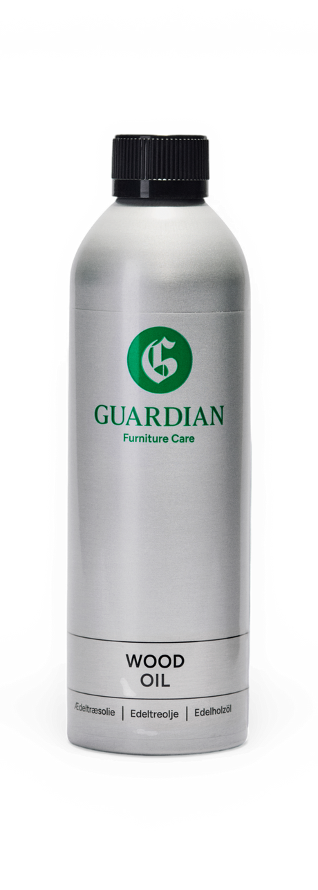 Silverfärgad flaska Guardian Furniture Care Wood Oil med svart kork på svart bakgrund.