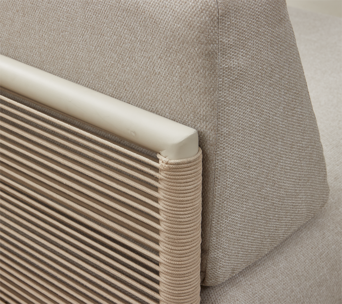 Närbild av beige soffrygg med texturerad kudde och armlänsdetalj lindad med snöre.