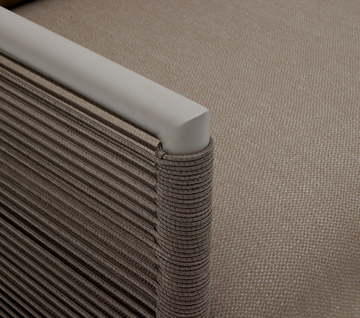 Närbild av en beige loungestols armstöd med repvävd sida.