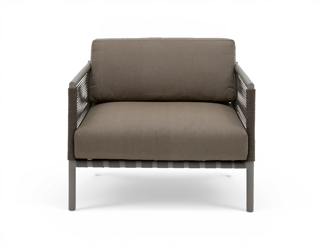 Modern loungefåtölj i taupe med repomspunna armstöd och smala metallben, frontvy på vit bakgrund.