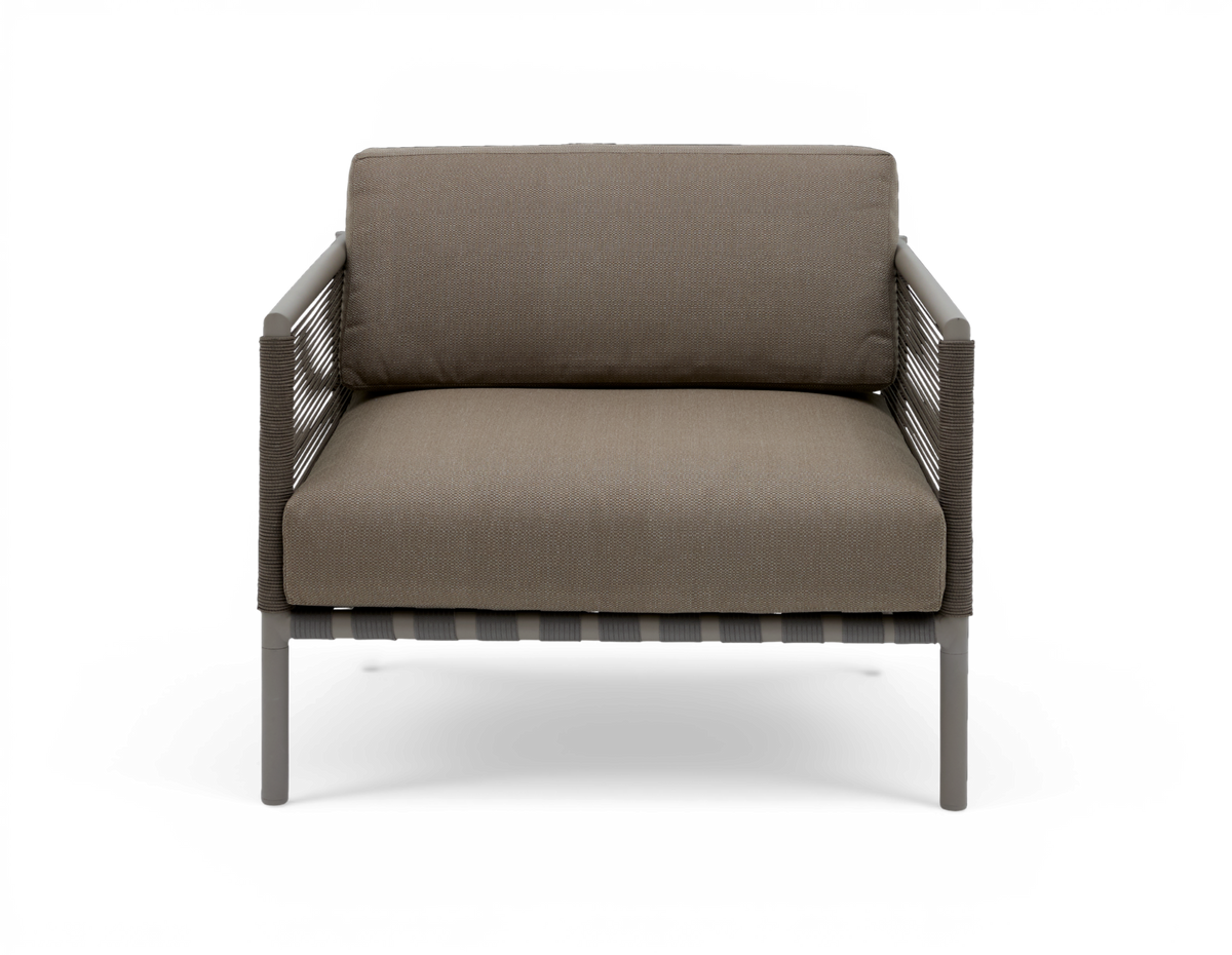 Modern loungefåtölj i taupe med repomspunna armstöd och smala metallben, frontvy på vit bakgrund.