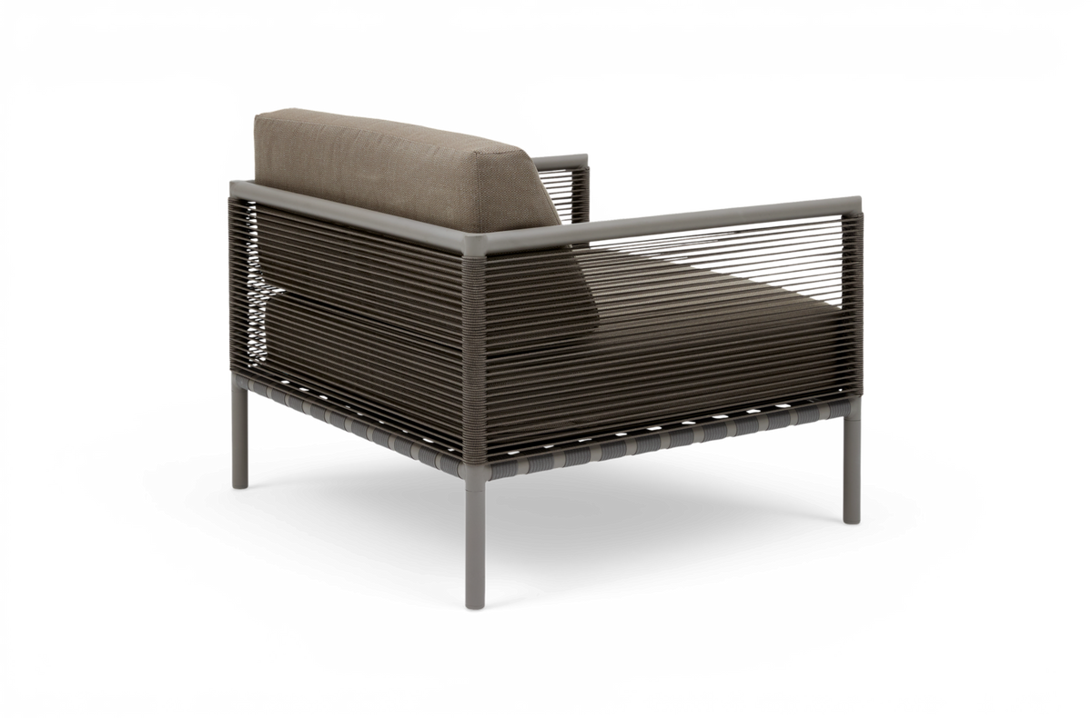 Modern loungestol med taupefärgad dyna och snörad ram i metall, visad bakifrån i frilagd studiomiljö.