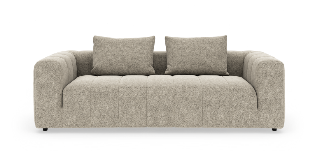 Beige tresitssoffa med två ryggkuddar, rundade armstöd och kanalsydd sits.