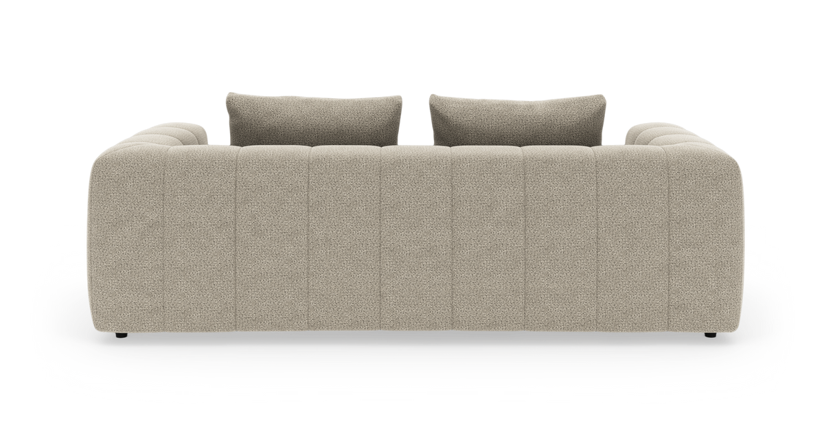 Beige modulsoffa sedd bakifrån med två ryggkuddar, isolerad på vit bakgrund i studiomiljö.
