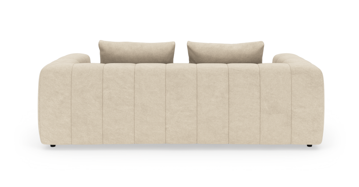Beigefärgad, modern soffa med afrundade armstöd och lodräta paneler, sedd rakt framifrån, med två ryggkuddar.