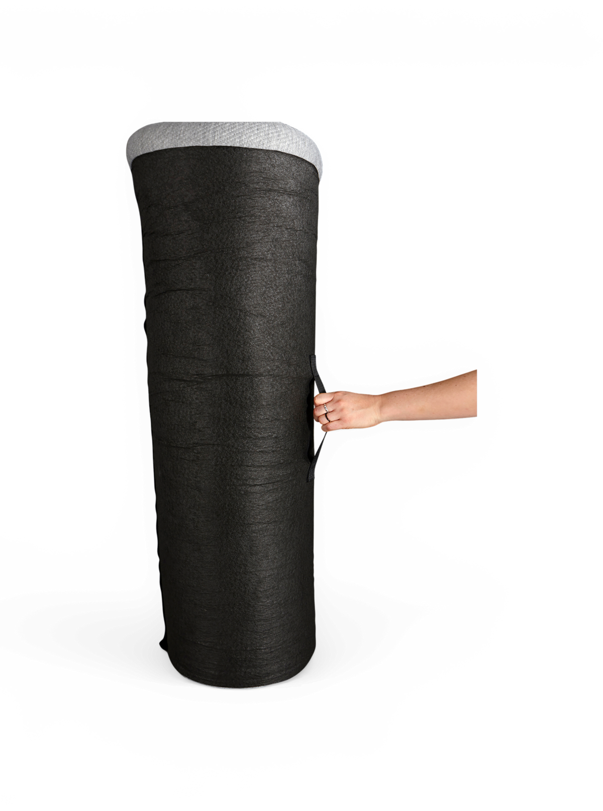 Stor svart cylindrisk tygkruka/odlingspåse med grå kant och bärhandtag, hålls i sidan av en hand, frilagd på vit bakgrund.