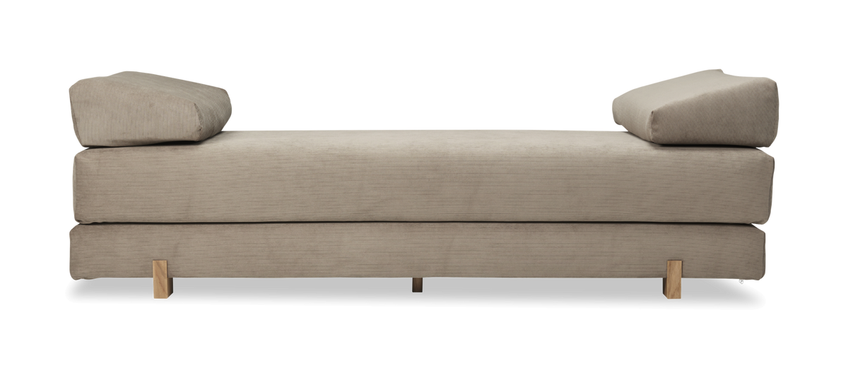 Beige dagbädd i manchester med två kilformade kuddar och träben.