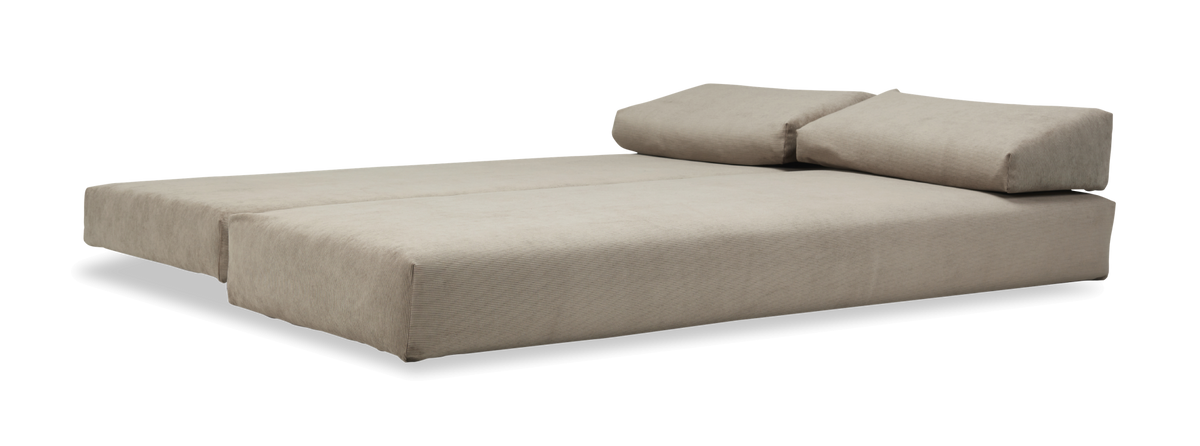Beige modulsoffa/säng i utfällt läge med två ryggkuddar, frilagd på neutral bakgrund.