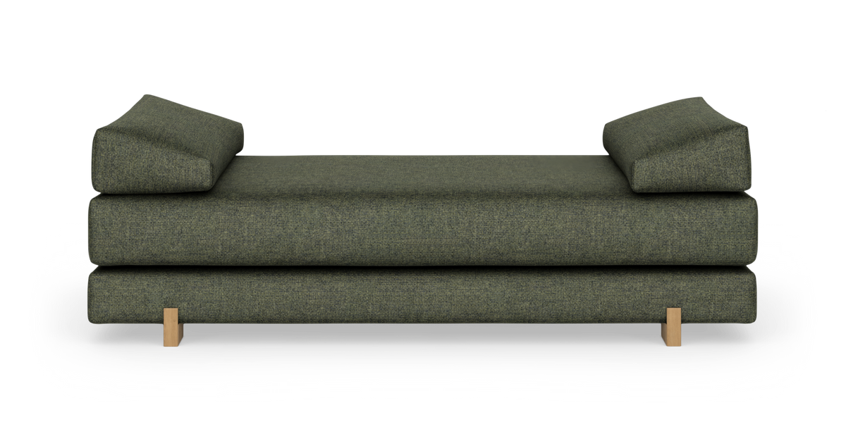 Grön daybed/soffa med två kilformade ryggkuddar och träben, frilagd på vit bakgrund.