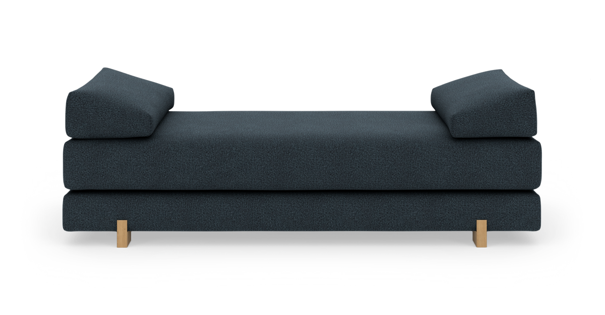Mörkblå daybed/soffa med två lutande armstöd och ljusa träben, frontvy mot vit bakgrund.
