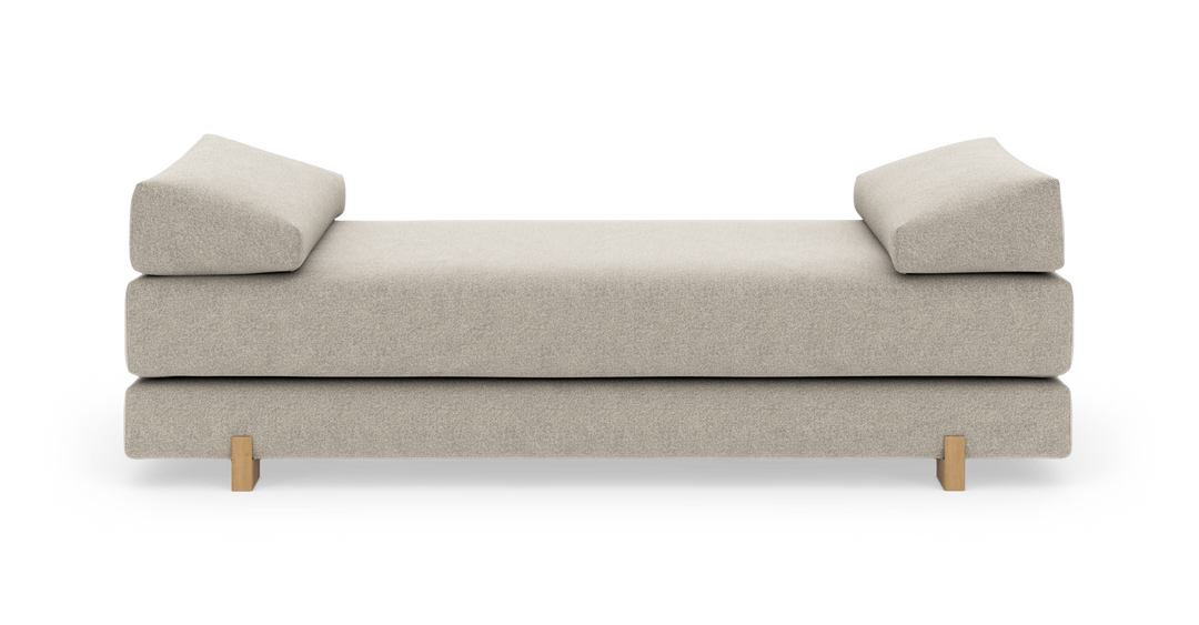 Beige dagbädd med två vinklade armstödskuddar och ljusa träben, frilagd på vit bakgrund.