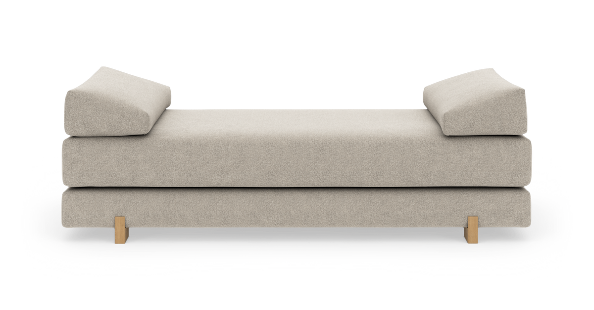 Beige dagbädd med två vinklade armstödskuddar och ljusa träben, frilagd på vit bakgrund.