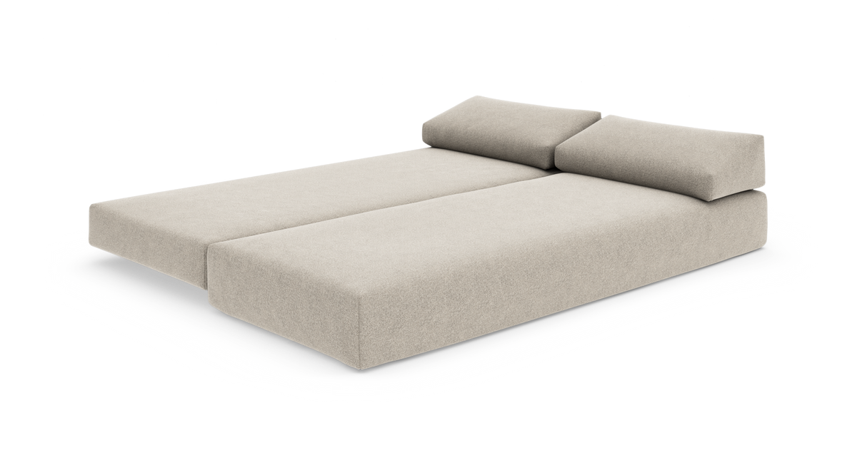 Beige modulsoffa utfälld till dubbelsäng med två ryggkuddar, frilagd på vit bakgrund.