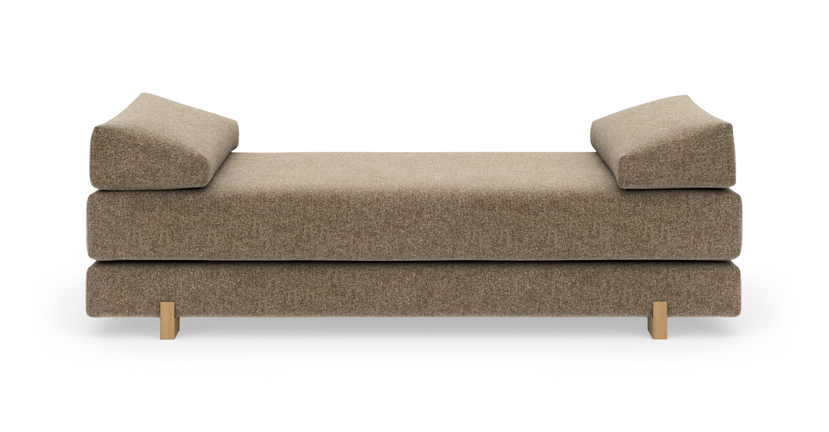 Beige dagbädd med kilformade armstöd och träben, frilagd mot vit bakgrund.